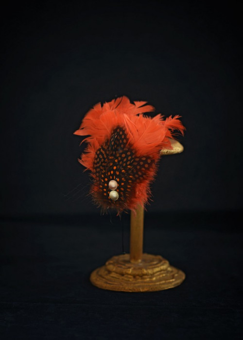 Orange headpiece with feathers mounted on headband 